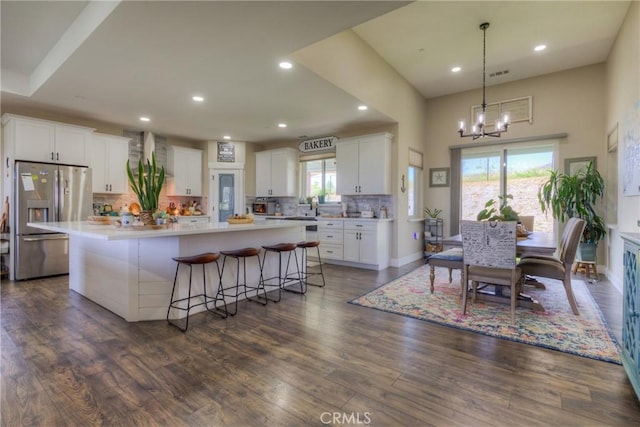 kitchen featuring decorative backsplash, a large island, stainless steel fridge with ice dispenser, dark wood-style floors, and white cabinetry