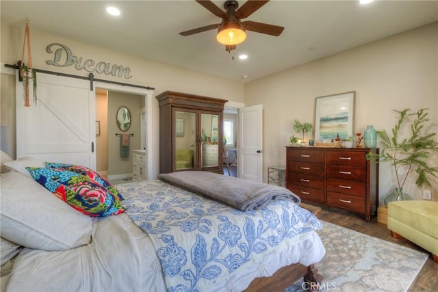 bedroom featuring recessed lighting, ceiling fan, a barn door, and wood finished floors
