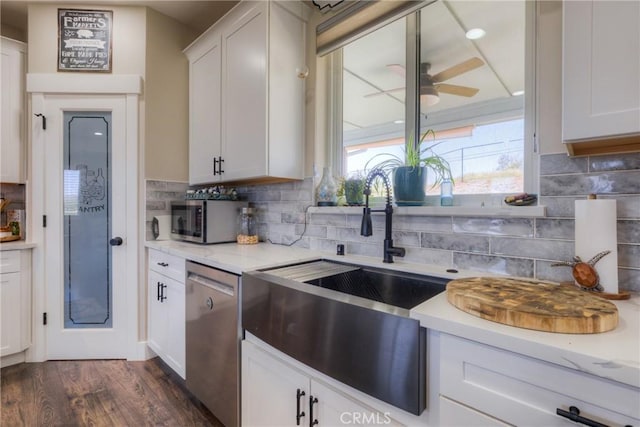 kitchen with a ceiling fan, dark wood-style floors, tasteful backsplash, a sink, and stainless steel appliances