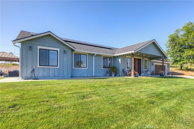 single story home with board and batten siding, a front yard, and solar panels