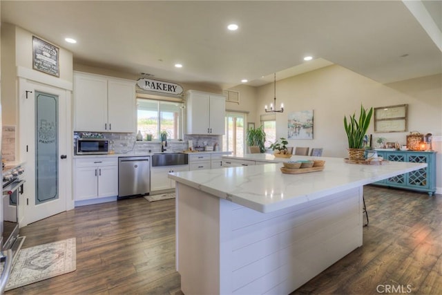 kitchen featuring a sink, a chandelier, dark wood finished floors, stainless steel appliances, and white cabinetry