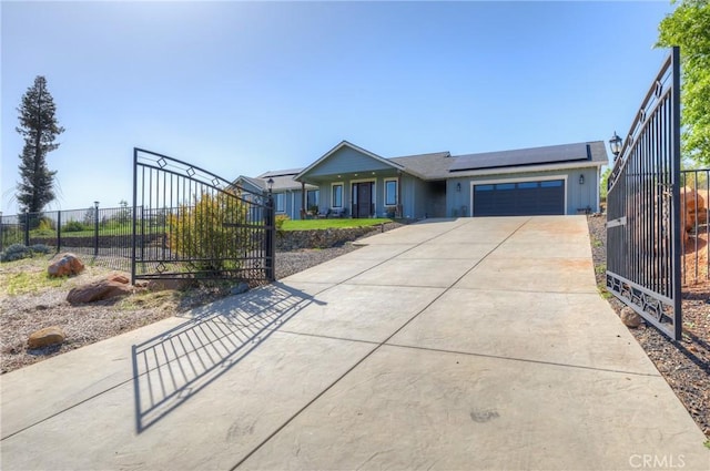 view of front of property with fence, a garage, a gate, concrete driveway, and solar panels
