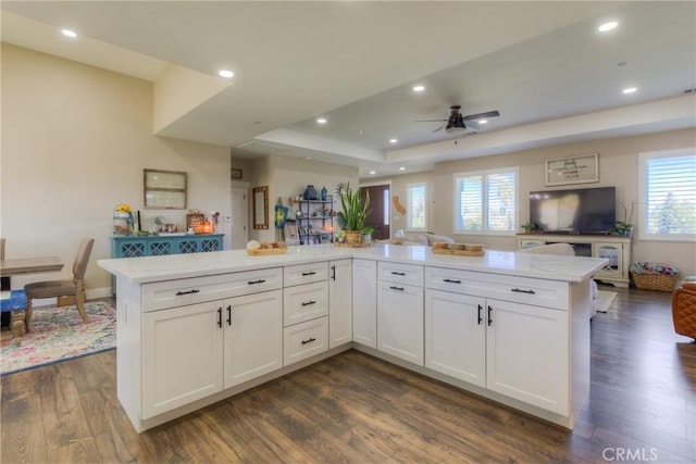 kitchen with ceiling fan, a raised ceiling, white cabinetry, open floor plan, and dark wood-type flooring