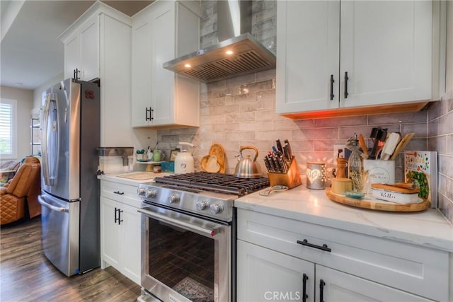 kitchen featuring white cabinets, dark wood-style flooring, light stone counters, wall chimney exhaust hood, and stainless steel appliances