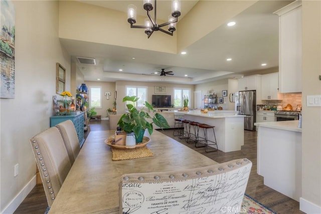 dining space with recessed lighting, a tray ceiling, visible vents, and dark wood finished floors