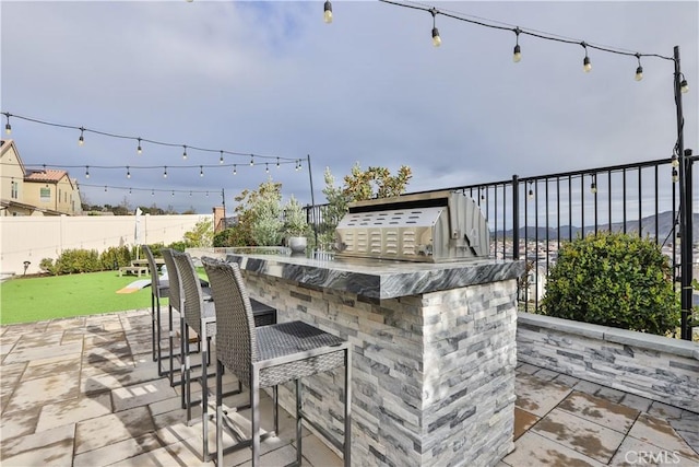 view of patio with fence, outdoor wet bar, and area for grilling