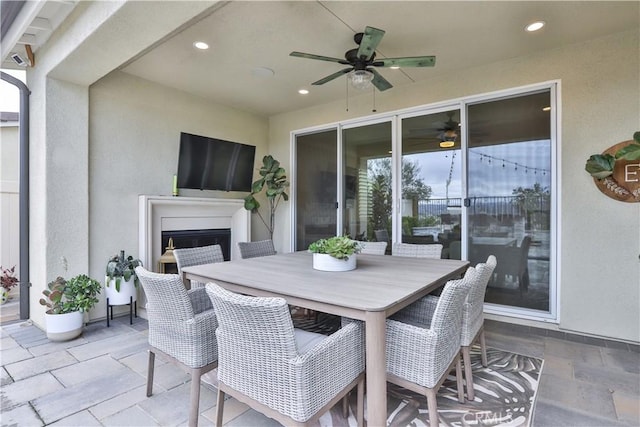 view of patio with a ceiling fan, outdoor dining space, and exterior fireplace