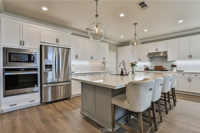 2454 Nova Way, Corona, CA 92883 - kitchen with stainless steel appliances, a sink, under cabinet range hood, light countertops, and backsplash