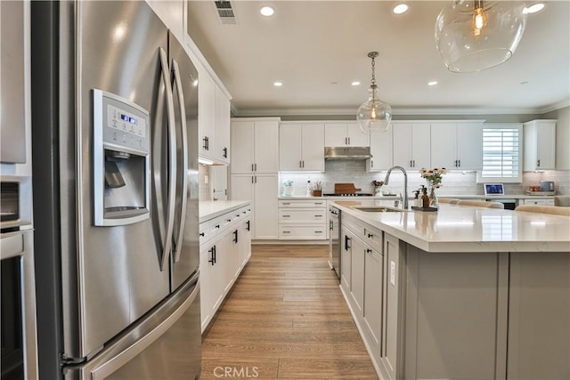 kitchen with crown molding, a sink, stainless steel fridge with ice dispenser, backsplash, and under cabinet range hood