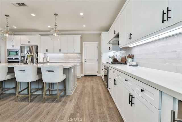 2454 Nova Way, Corona, CA 92883 - kitchen featuring stainless steel appliances, ornamental molding, backsplash, a breakfast bar area, and under cabinet range hood