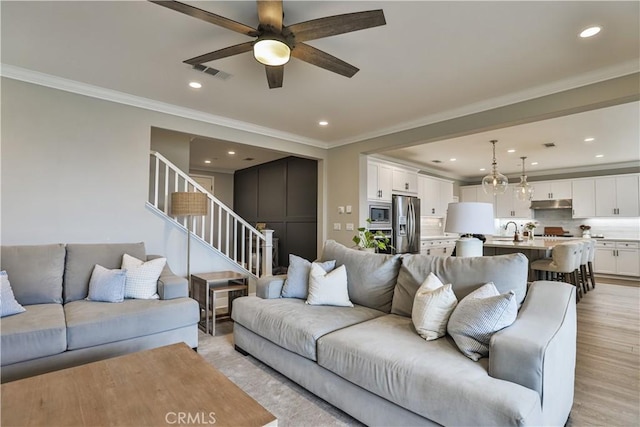 living room with ceiling fan, light wood-style flooring, recessed lighting, visible vents, and stairway