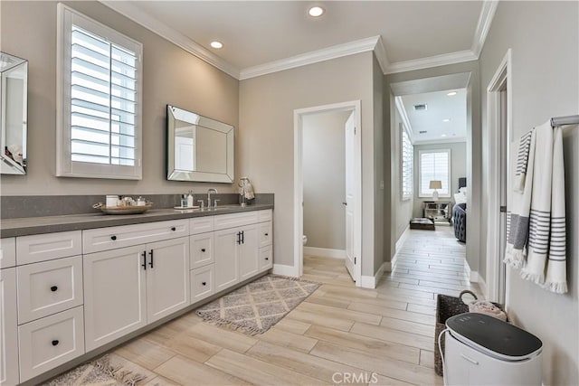 full bath featuring wood finished floors, vanity, baseboards, toilet, and ornamental molding
