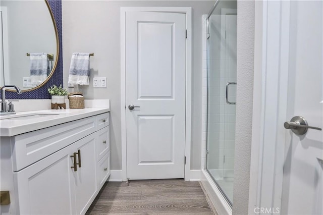 full bathroom featuring vanity, a shower stall, and wood finished floors