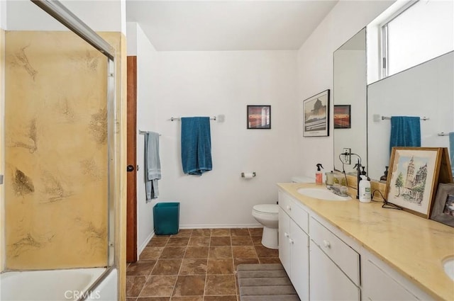 bathroom featuring baseboards, a sink, double vanity, and toilet