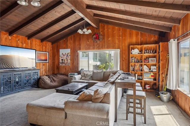 carpeted living area featuring vaulted ceiling with beams, wood ceiling, a notable chandelier, and wooden walls