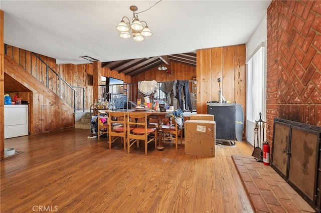 dining space featuring wood finished floors, wood walls, washer / clothes dryer, and a notable chandelier