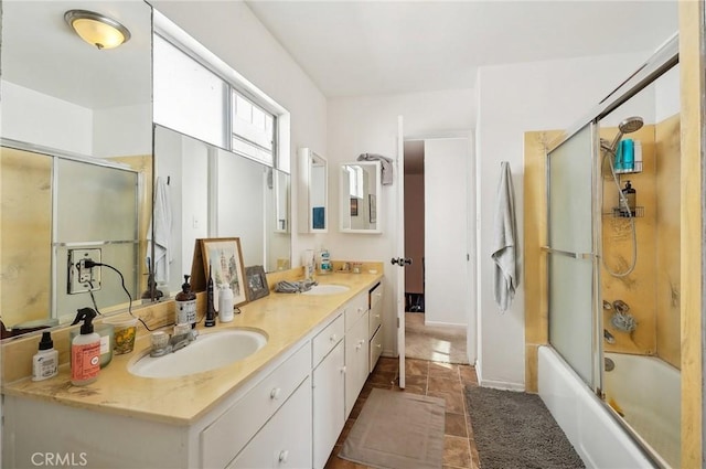 full bath with double vanity, a sink, and bath / shower combo with glass door