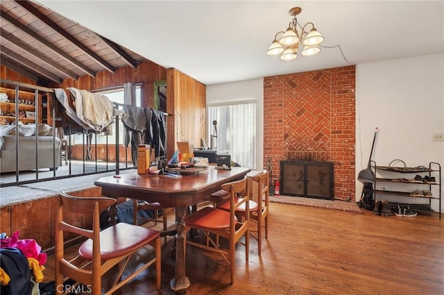 dining area with a notable chandelier, a healthy amount of sunlight, wood finished floors, and a fireplace