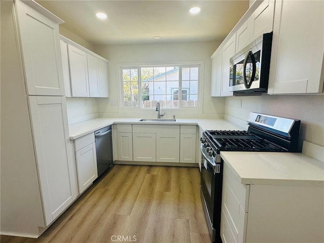 kitchen with light wood-style flooring, white cabinetry, recessed lighting, a sink, and stainless steel appliances