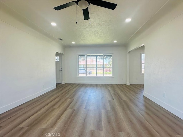 interior space with arched walkways, wood finished floors, and baseboards