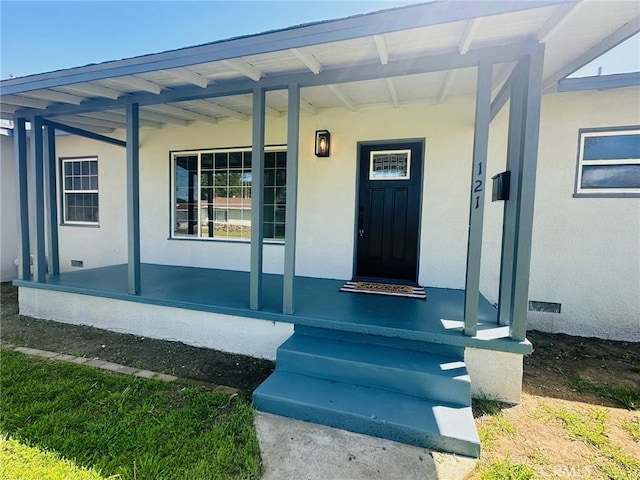 entrance to property featuring covered porch and stucco siding