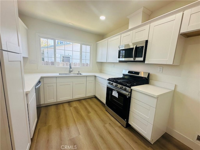 kitchen with light wood-style flooring, a sink, white cabinetry, and stainless steel appliances