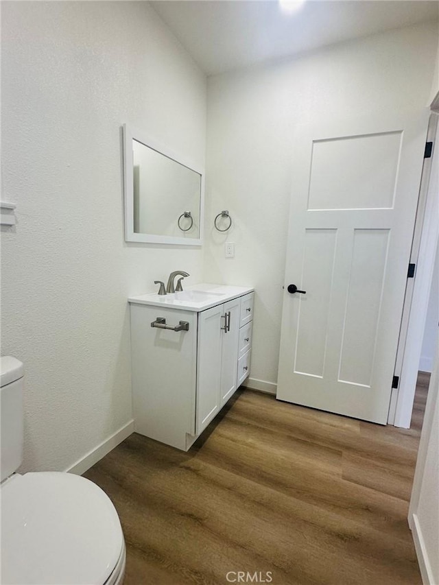 bathroom featuring vanity, baseboards, toilet, and wood finished floors