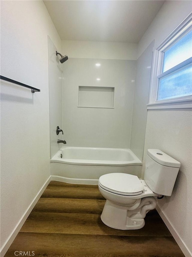full bathroom featuring bathing tub / shower combination, baseboards, toilet, and wood finished floors
