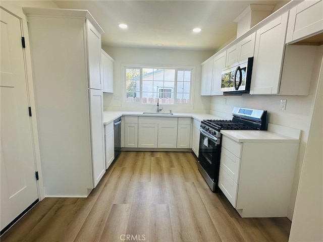 kitchen with light wood-style flooring, white cabinetry, a sink, and appliances with stainless steel finishes