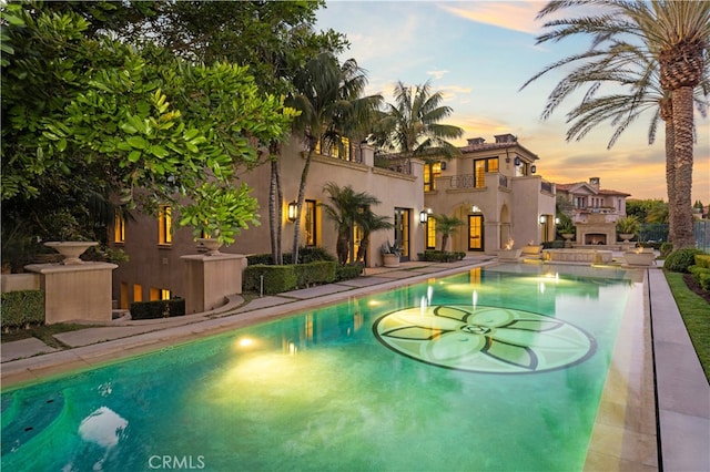 9 Shoreridge, Newport Coast, CA 92657 - pool at dusk with an outdoor pool, an outdoor fireplace, and a patio area