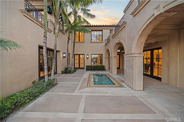 9 Shoreridge, Newport Coast, CA 92657 - exterior entry at dusk featuring french doors, a patio, and stucco siding