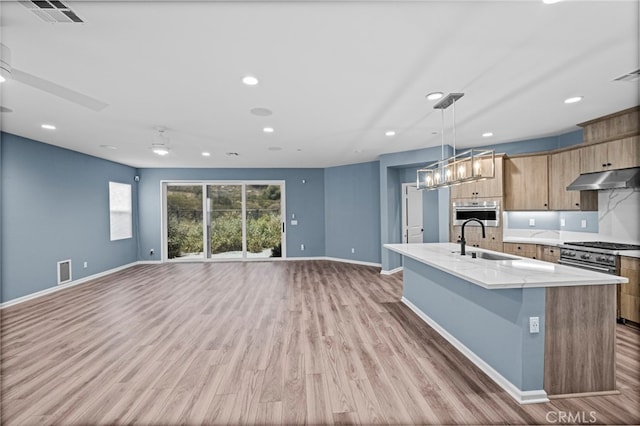1373 Topanga Dr, San Marcos, CA 92069 - kitchen with under cabinet range hood, a center island with sink, light wood-style flooring, recessed lighting, and pendant lighting