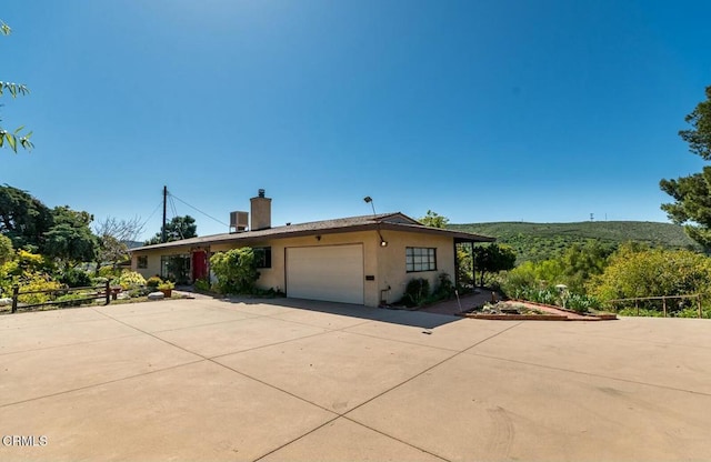 view of front of home featuring a garage, driveway, stucco siding, and a chimney