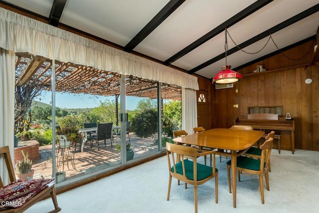 dining room with wooden walls, vaulted ceiling with beams, and a healthy amount of sunlight