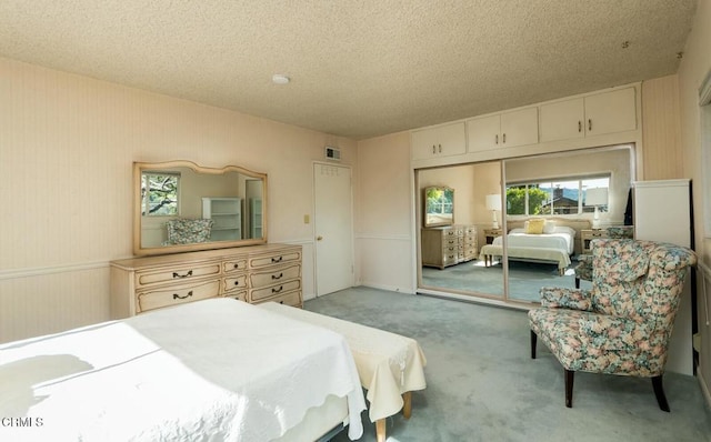 bedroom with carpet floors, a closet, visible vents, and a textured ceiling