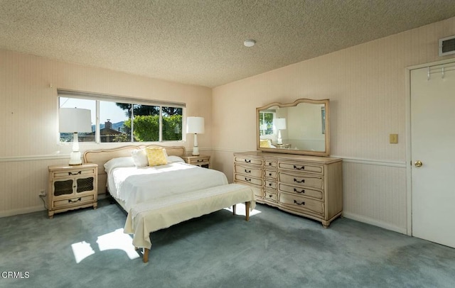 carpeted bedroom with visible vents, wainscoting, and a textured ceiling