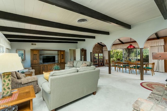 living area featuring visible vents, beam ceiling, and carpet