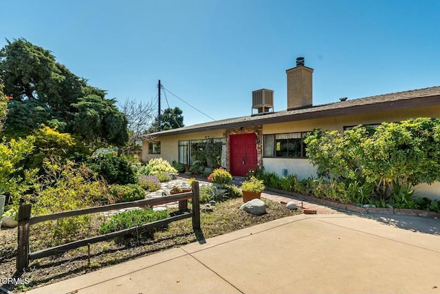 single story home featuring cooling unit, fence, and a chimney
