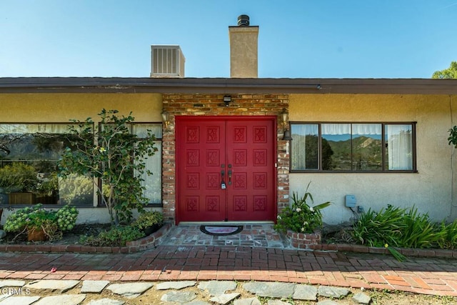property entrance featuring a chimney and stucco siding