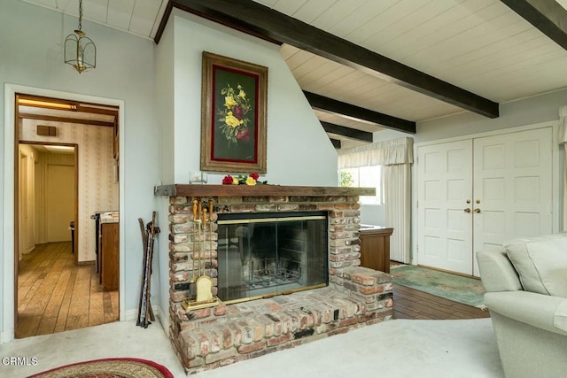 living area with visible vents, vaulted ceiling with beams, hardwood / wood-style floors, and a fireplace