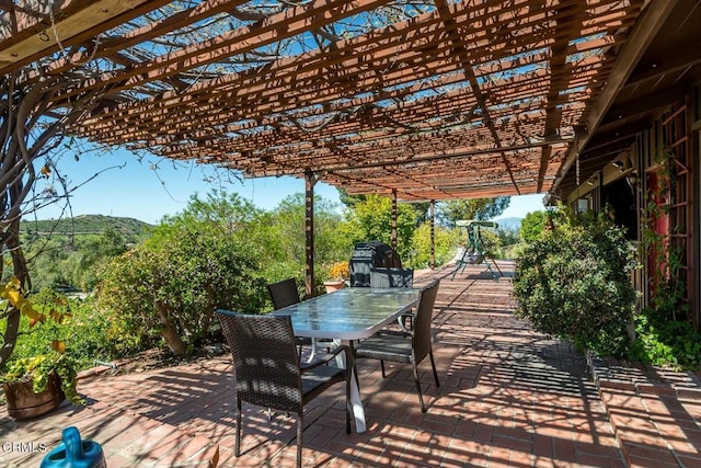 view of patio with a mountain view, outdoor dining space, and a pergola