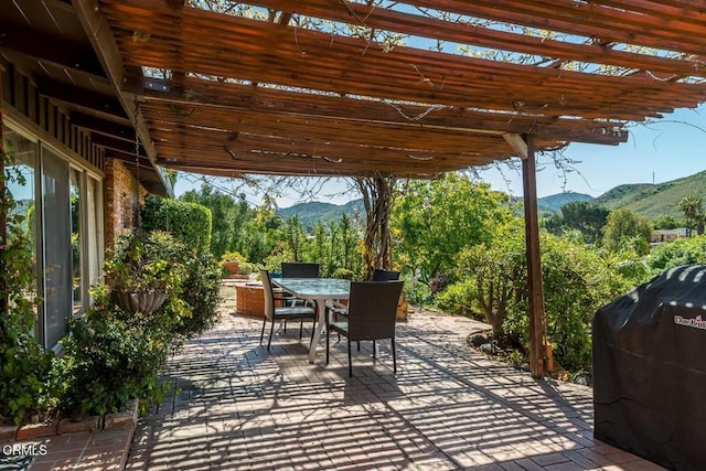 view of patio / terrace with a grill, outdoor dining space, a mountain view, and a pergola