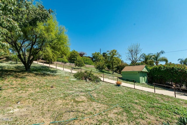 view of yard featuring fence, an outbuilding, and a storage unit