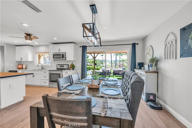 dining room featuring plenty of natural light, light wood-type flooring, baseboards, a ceiling fan, and recessed lighting