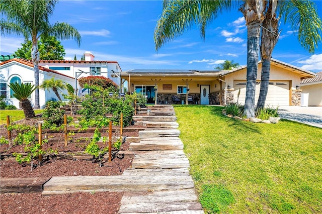view of front of property with a front yard, stucco siding, roof mounted solar panels, a garage, and concrete driveway