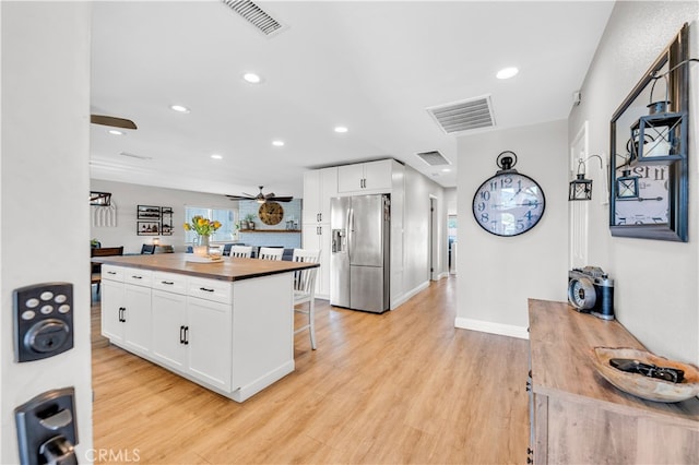 kitchen featuring stainless steel refrigerator with ice dispenser, butcher block countertops, ceiling fan, white cabinets, and recessed lighting