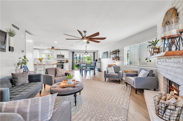living area featuring a brick fireplace, light wood-type flooring, ceiling fan, and recessed lighting