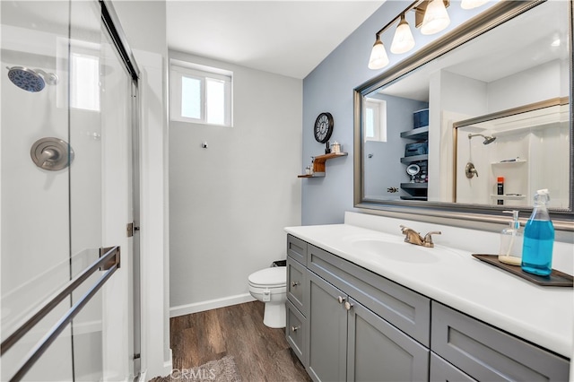 bathroom featuring a shower stall, wood finished floors, vanity, baseboards, and toilet