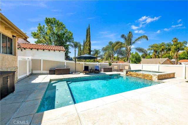 view of pool with a patio, a fenced backyard, and a pool with connected hot tub