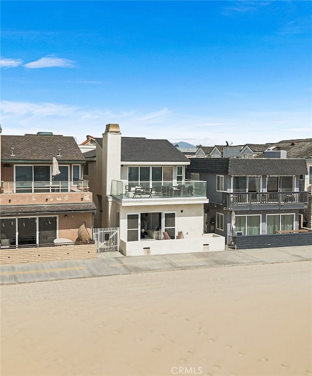 3012 W Oceanfront, Newport Beach, CA 92663 - rear view of house with a balcony and stucco siding